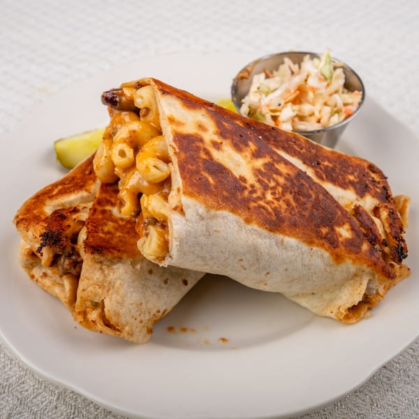 Two golden-brown burritos filled with macaroni and cheese, served with coleslaw and a pickle.