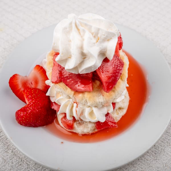Strawberry shortcake with whipped cream and strawberry sauce on a white plate at Andy's Old Port Pub.