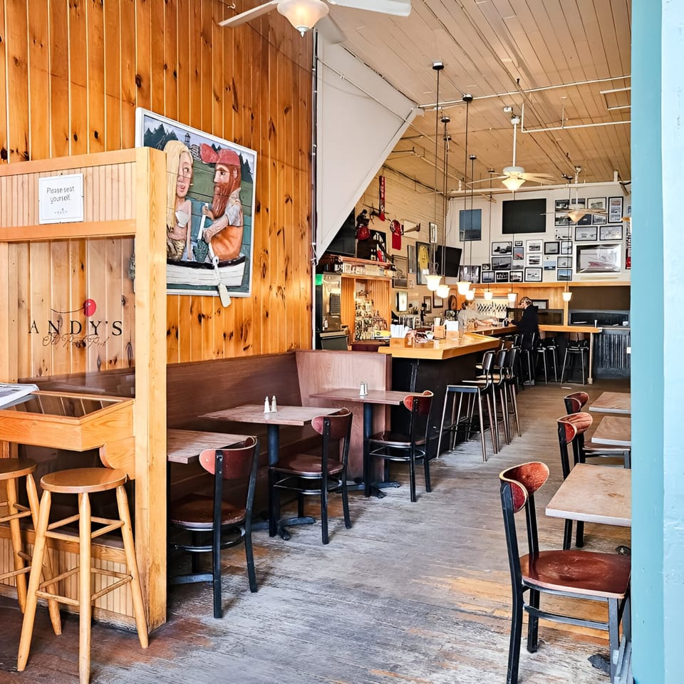 Interior of Andy's Old Port Pub, featuring wooden walls, tables, chairs, and a bar area.